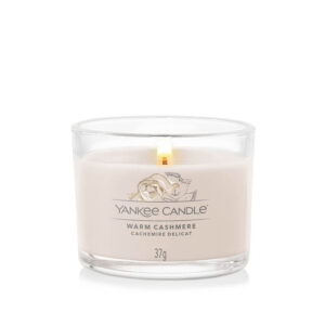 Proizvod Yankee Candle Warm Cashmere sveća u staklenoj čaši sa upaljenim plamenom.